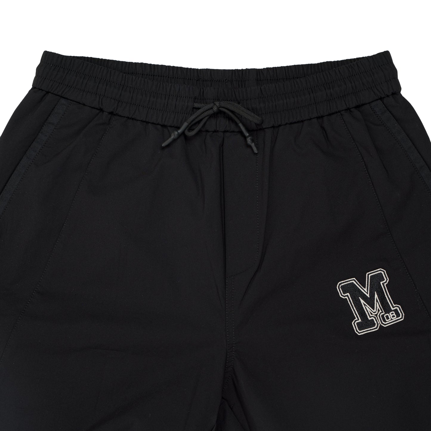 A close-up view of black pants showcasing the 'm' logo elegantly positioned on the side.