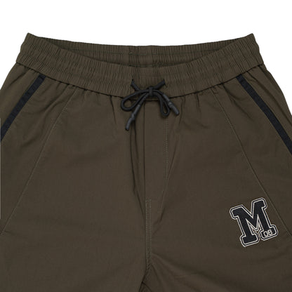 A close-up view of burnt green pants showcasing the 'm' logo elegantly positioned on the side.