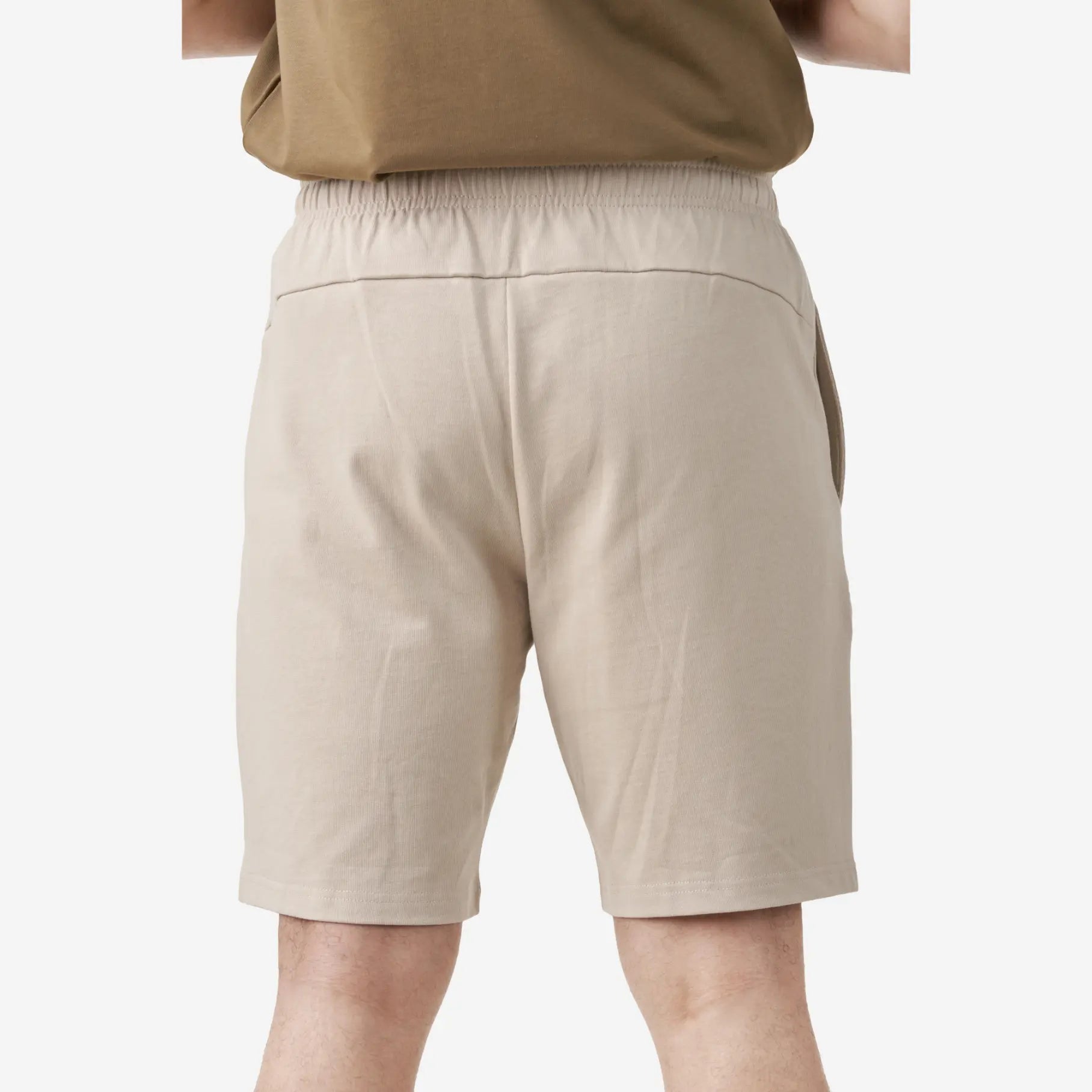 Back view of beige casual shorts featuring an elastic waistband, a smooth back design without pockets, and a relaxed fit.